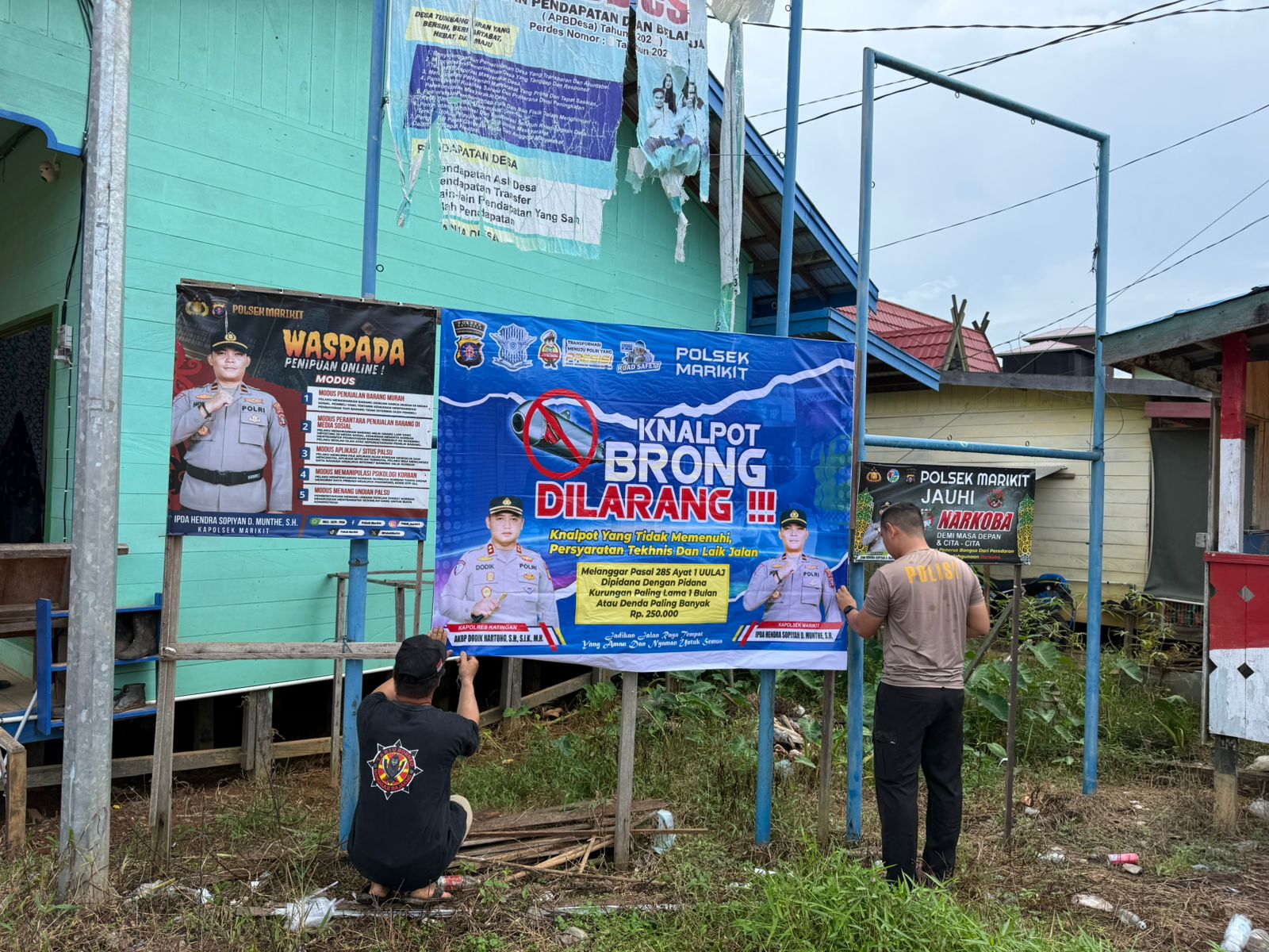 PERSONEL POLSEK MARIKIT PASANG SPANDUK IMBAUAN KAMTIBMAS DI PASAR DESA TUMBANG HIRAN